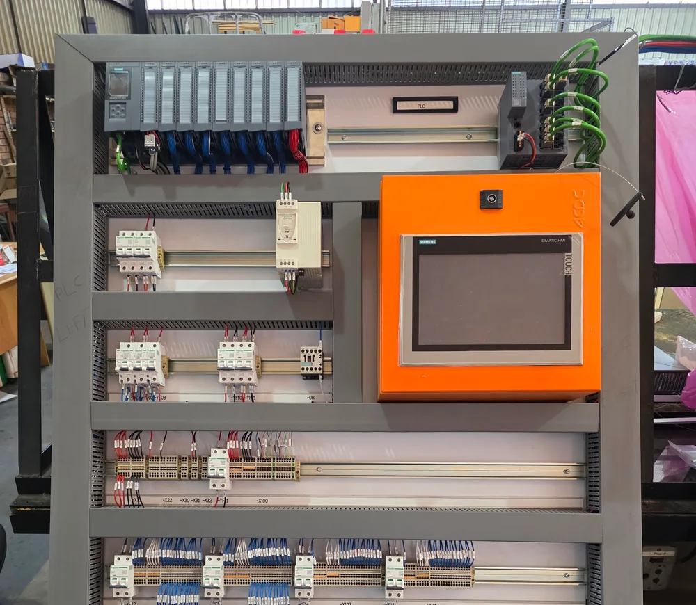 Control panel with a PLC rack, orange operator interface and labelled terminal wiring